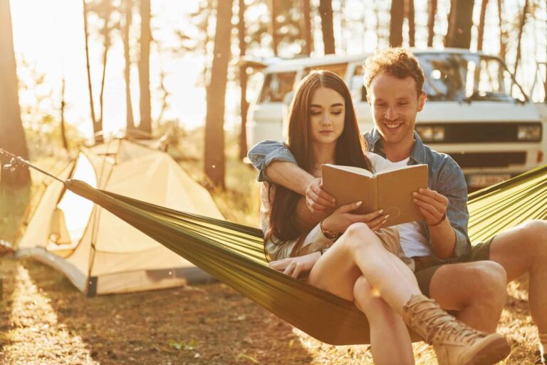 Holding book. Young couple is traveling in the forest at daytime together